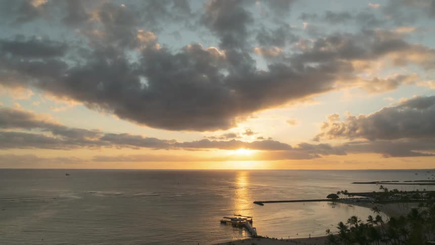 The sun sets in a cloudy sky on an ocean horizon