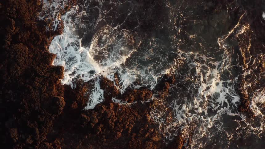 Ocean waves crash and splash against the rocky shore