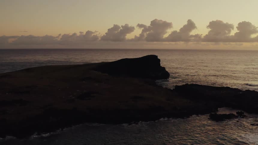 Aerial footage of small island in ocean at sunset