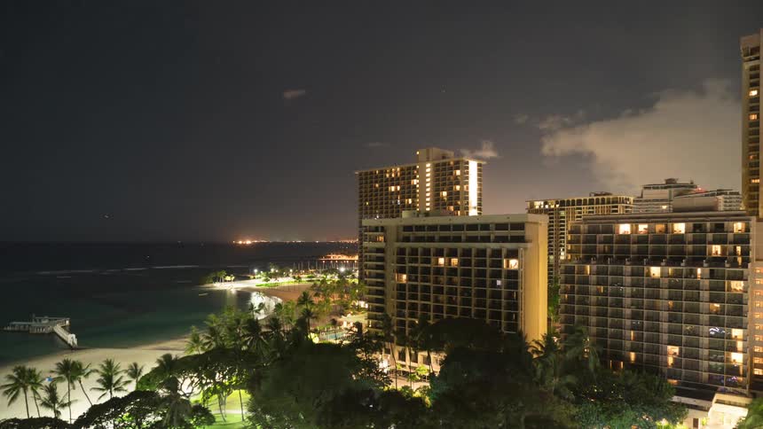 Clouds pass over buildings bordering park and beach