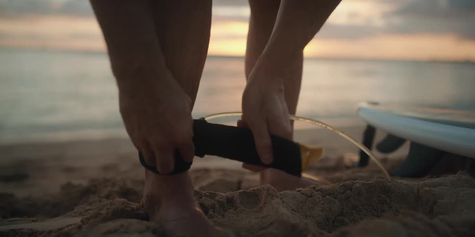 A surfer attaches a leash to their ankle