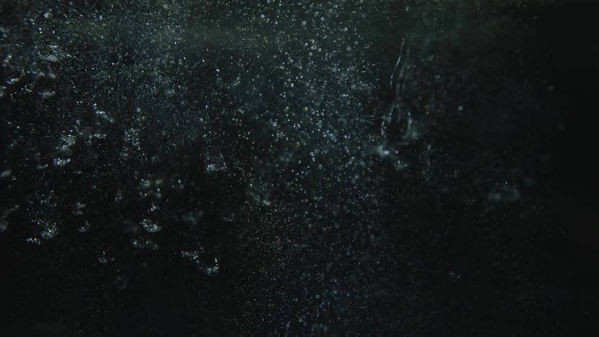 Pieces of shattered glass falling through water