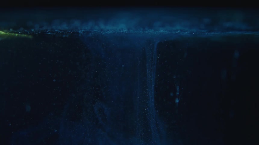 Abstract of blue liquid against black background with tiny bubbles rising
