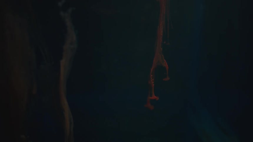 Orange fluid suspension in water against black background