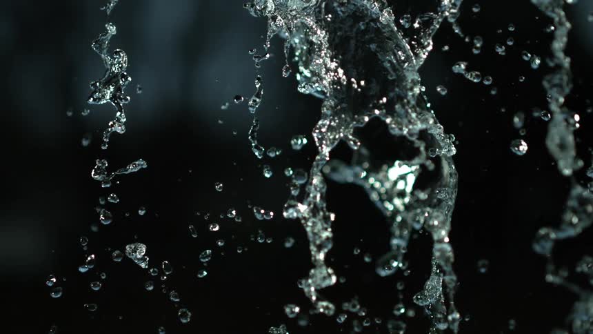 The water slowly sprays down reflecting light