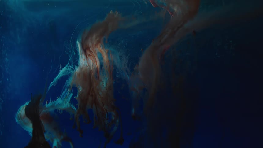 Brown and red ink floating in blue liquid