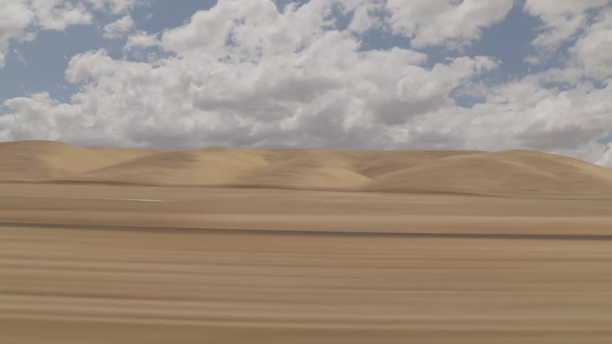 Cars drive down a highway through the desert