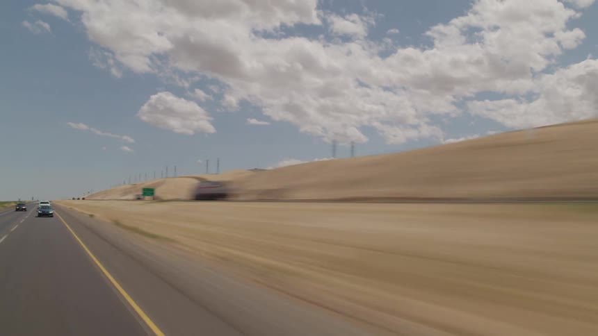A road with vehicles with the sky and clouds in the background