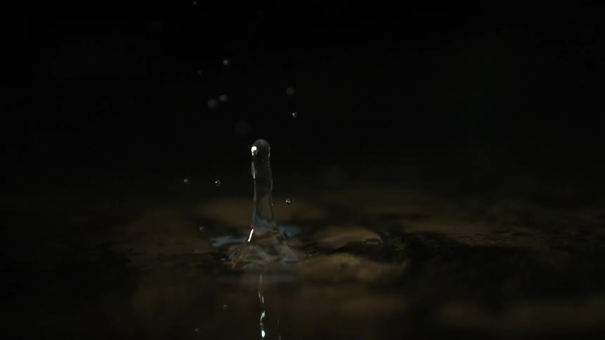 Water droplet falls on a water surface