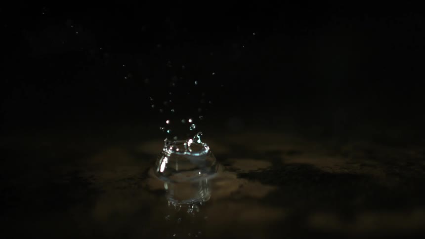 Drop of water falling in slow motion into a puddle