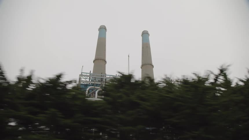 Two tall chimneys stand tall over factory at day