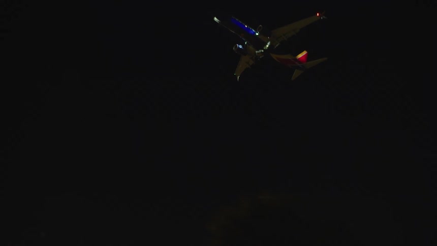 The plane flies high over the freeway at night