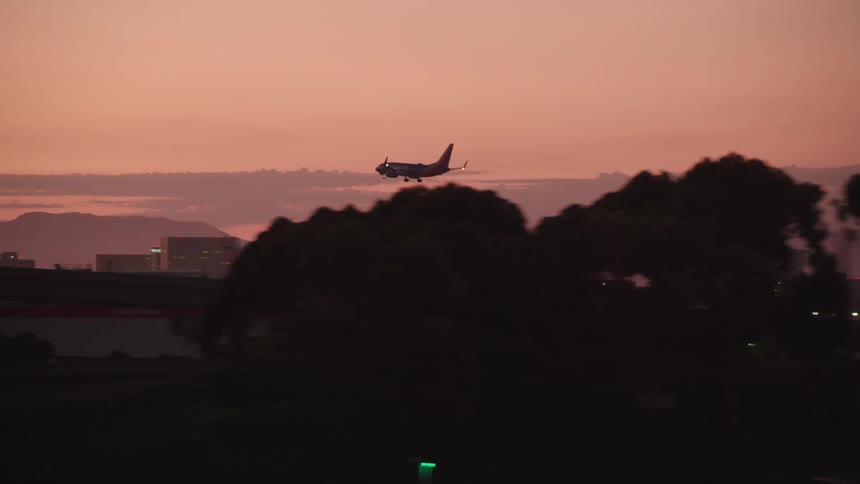 Airplane landing on city airport at sunset