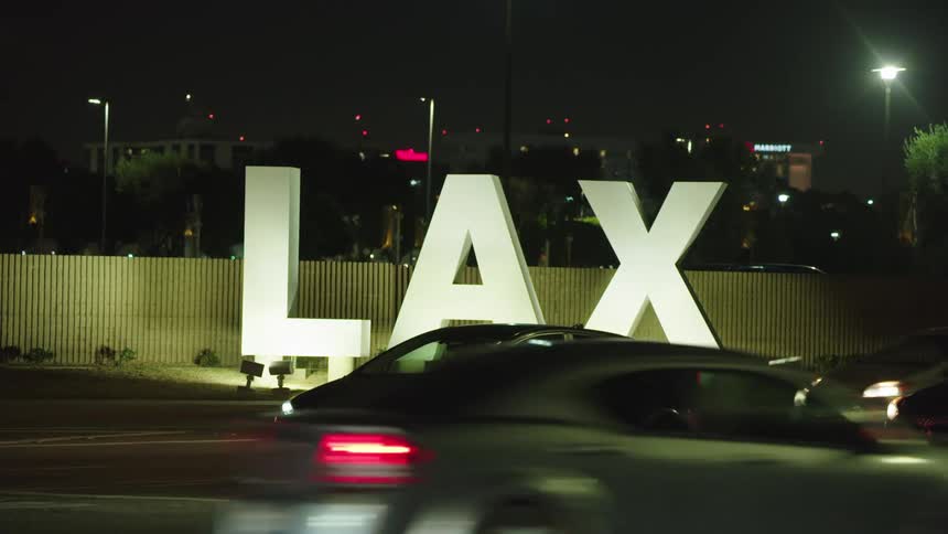 Car parked in front of lax airport sign as cars drive by
