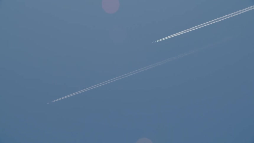 Two planes flying in the sky leaving white contrails