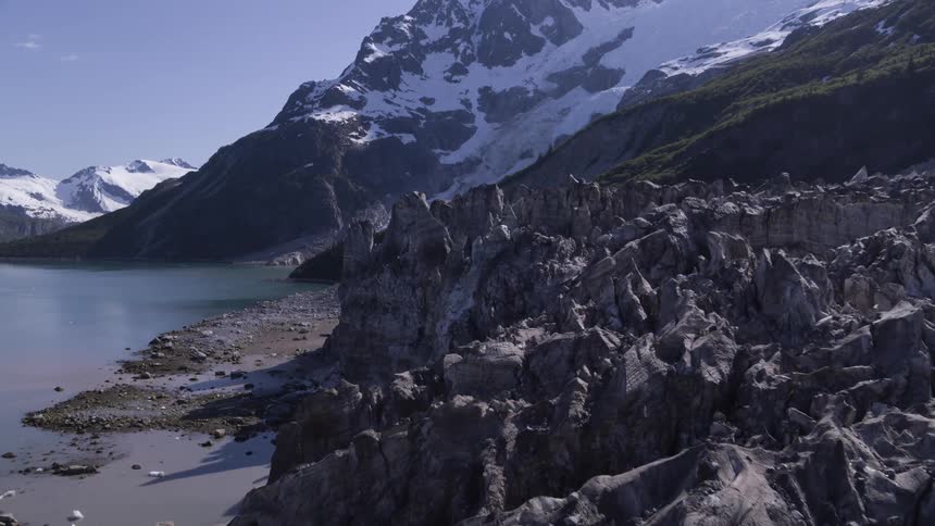 A rocky coastline of a lake in the valley of a snowy mountain