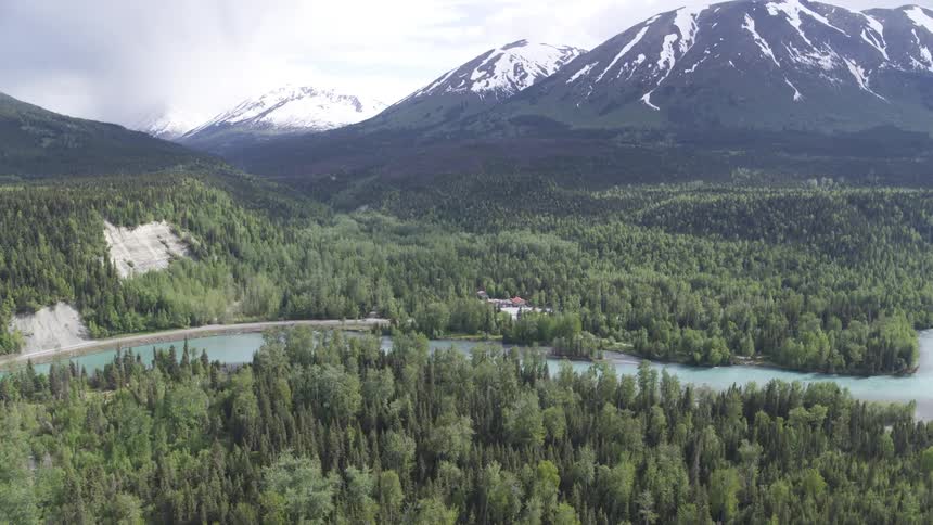 The river runs past the forest by the mountain range