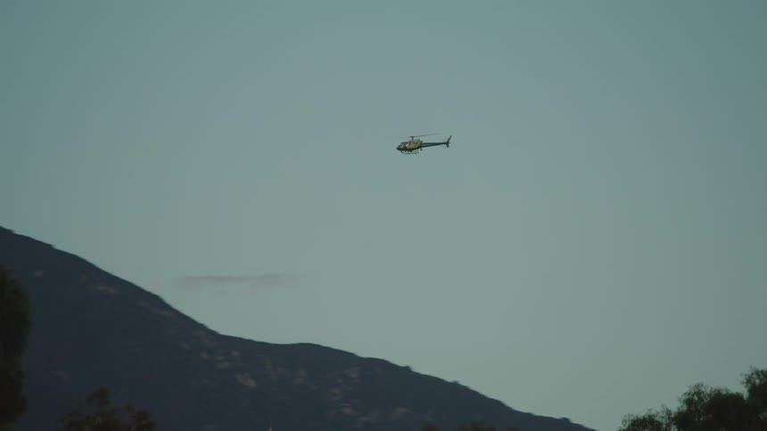 Helicopter flying near of mountain at sunset