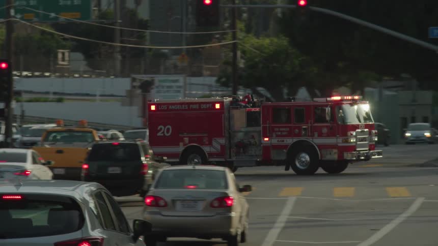 A fire truck with its lights flashing drives down the street