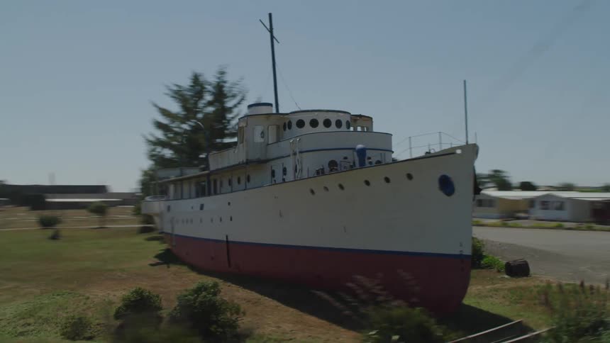 A boat near a road with trees in the background