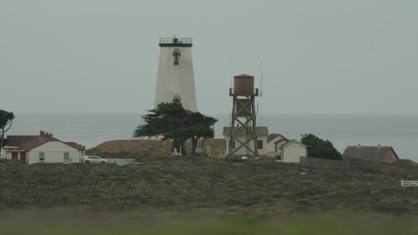 Fog sets over a lighthouse along the sea shore