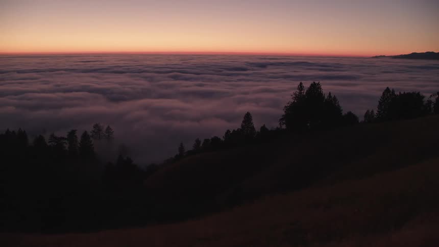 Hills with trees with a foggy lake and the sky in the background