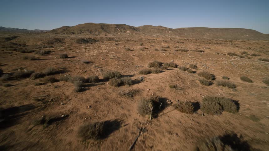 The hills are barren with small bushes in areas