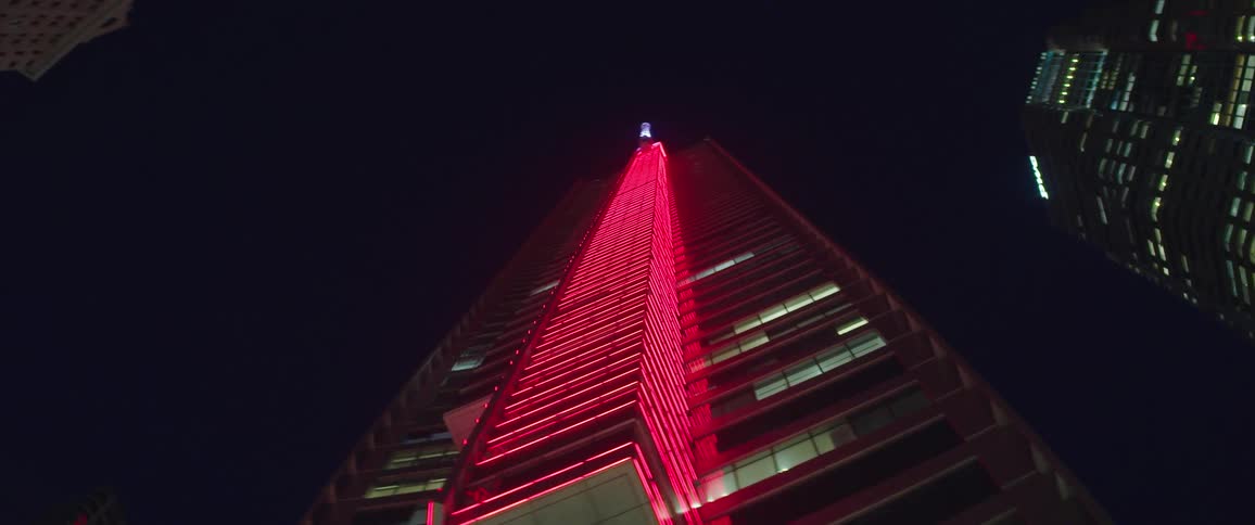 The building is lined with pink lights to the top