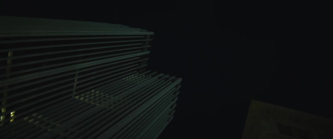 A camera stares straight up into the sky surrounded by towering buildings