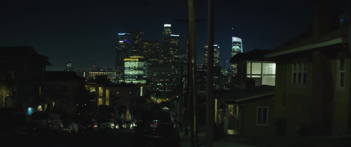 Illuminated buildings in a city sit under the night sky