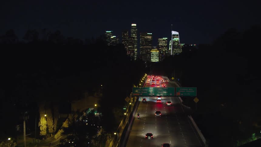 City skyline with urban skyscrapers and cars driving along highway at night