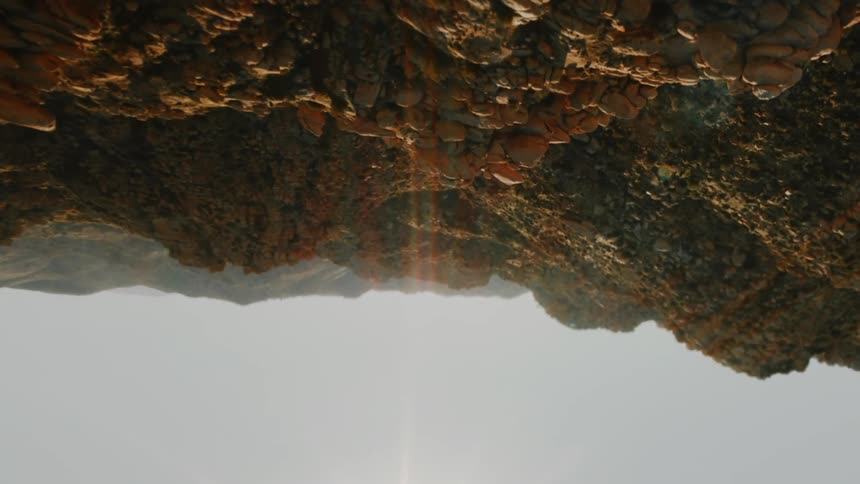 A rocky desert with the sky and the sun in the background