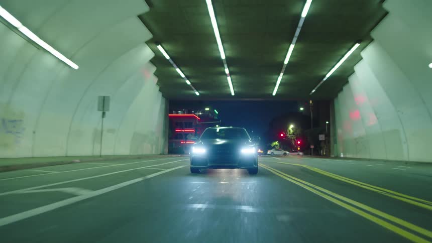 A car drives through a tunnel that a pedestrian walks in