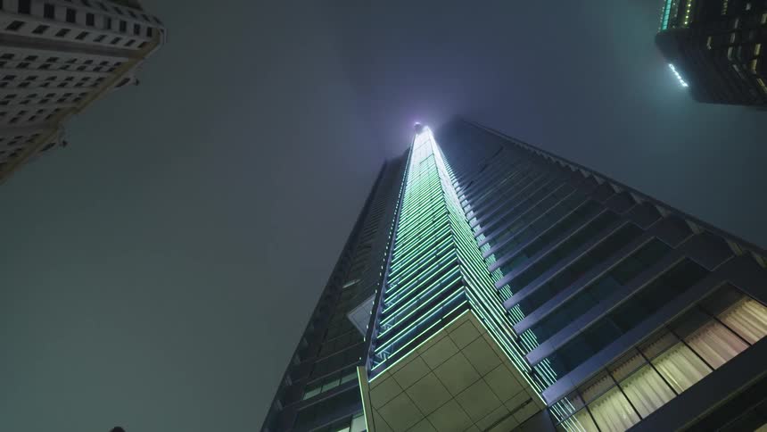 Street view looking up at tall skyscraper at night