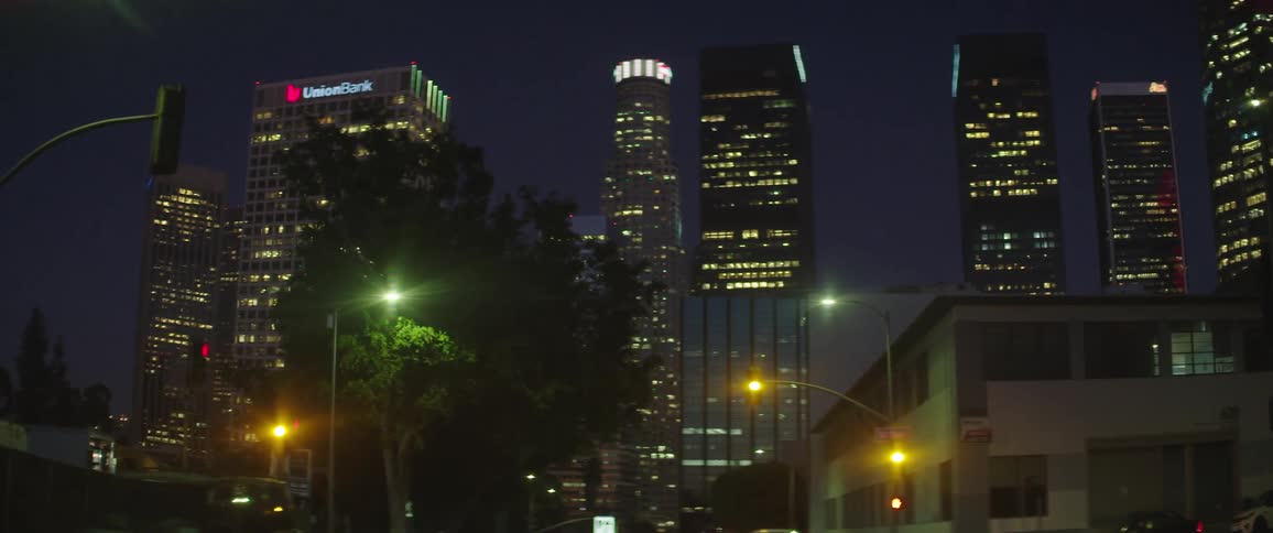 Traffic passes by tall buildings that make up a city skyline