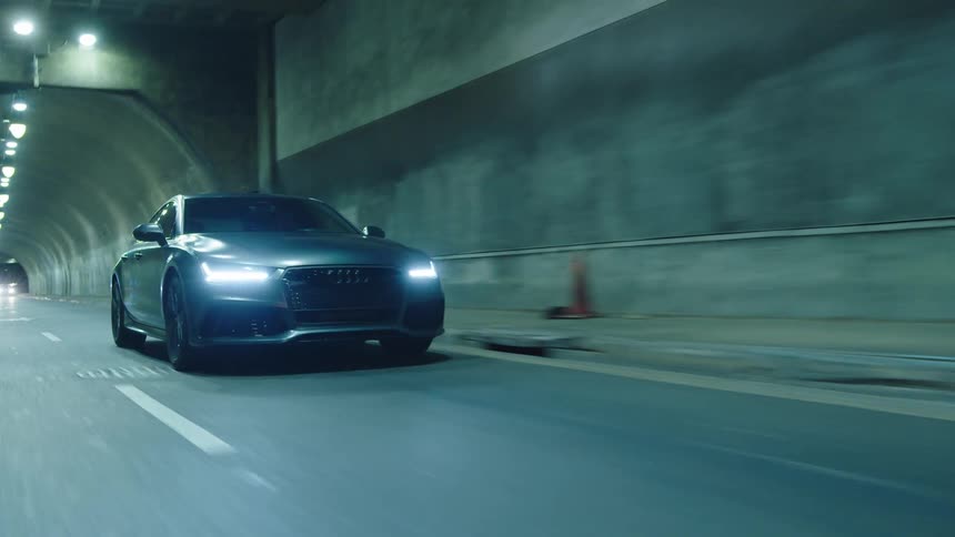 Cars travel through a tunnel with some graffiti on the walls