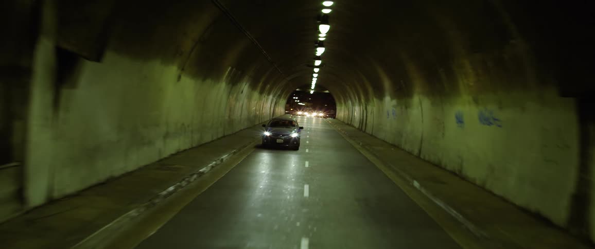 Vehicles travel through a dark tunnel at night