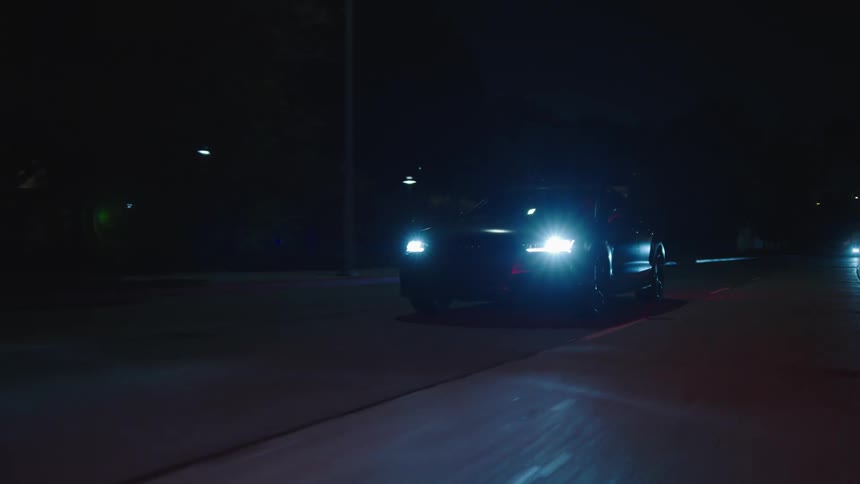 A car drives down the road at night