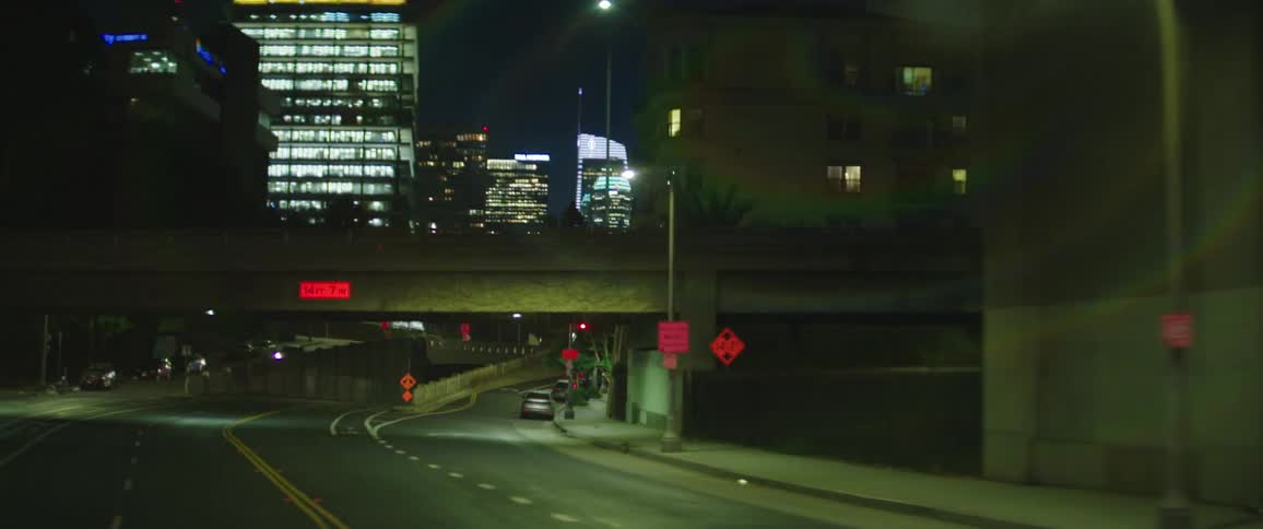 Cars are driving in a downtown city at night