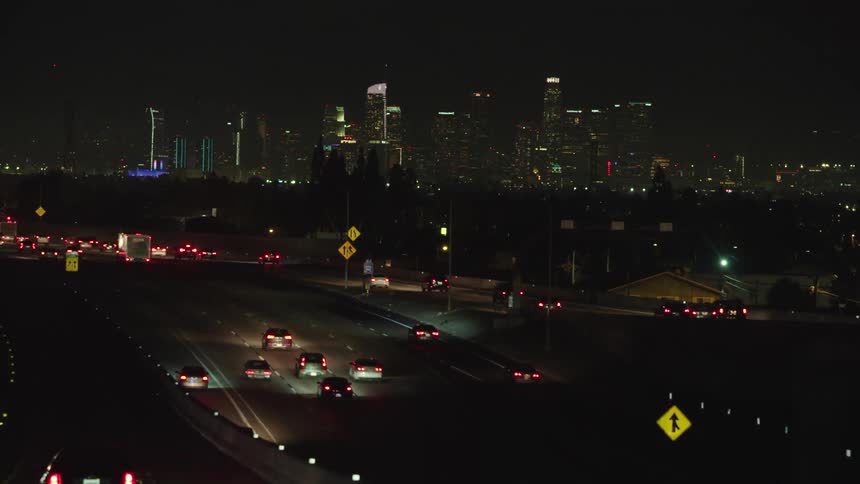 Distant illuminated cityscape with skyscrapers and traffic jam at night
