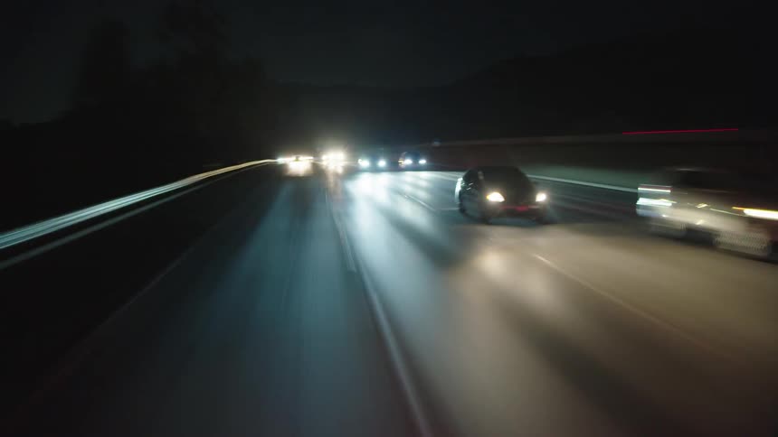 Cars drive on a busy highway at night