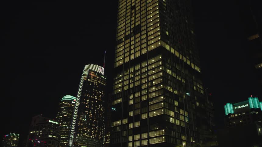 The tall buildings are brightly lit at night
