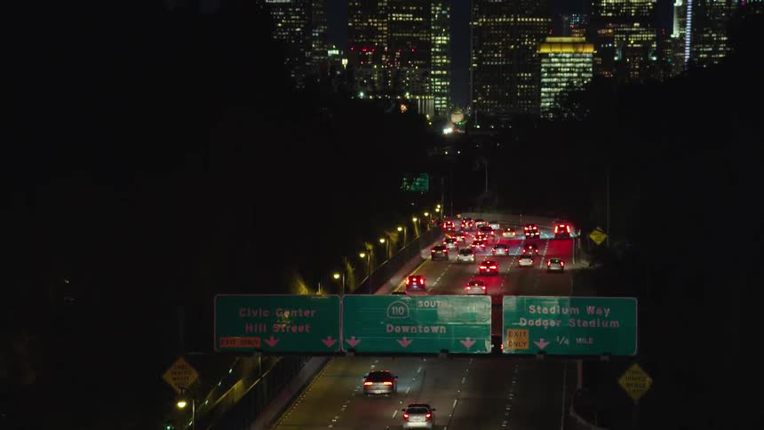 A highway at night with vehicles and the city skyline in the foreground