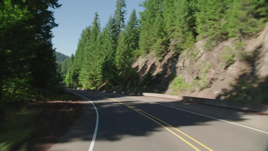 Back view of driving through the mountains on a curvy road