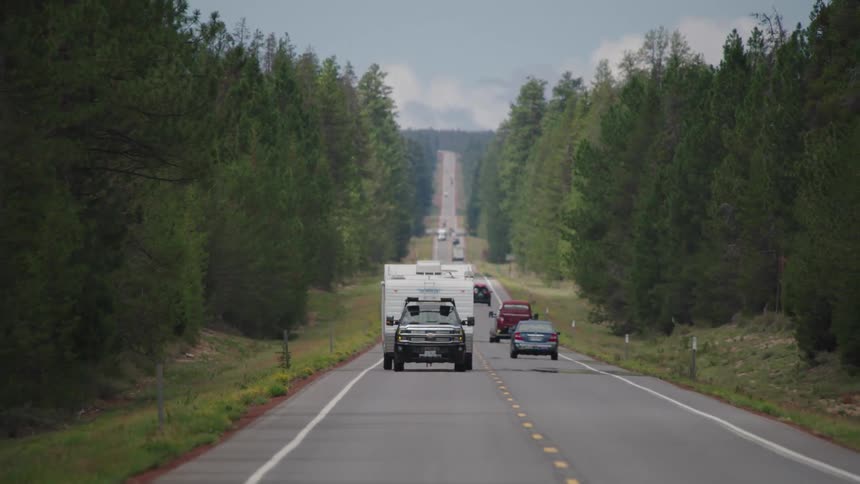 Truck pulling a trailer on road trip through the forest