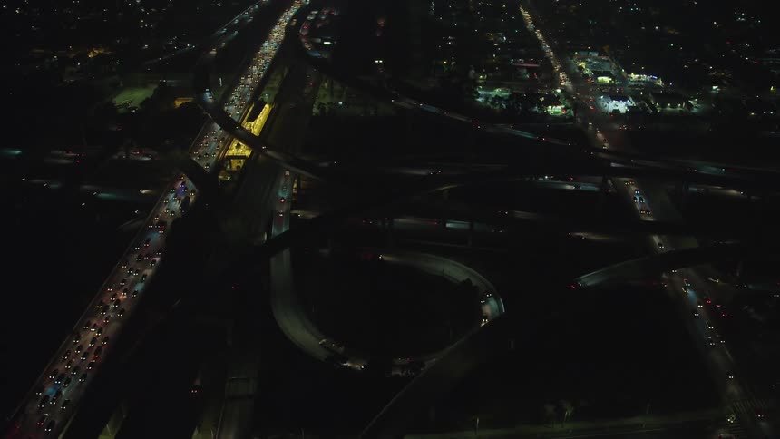Cars and truck travel on a city highway with loops and exits at night