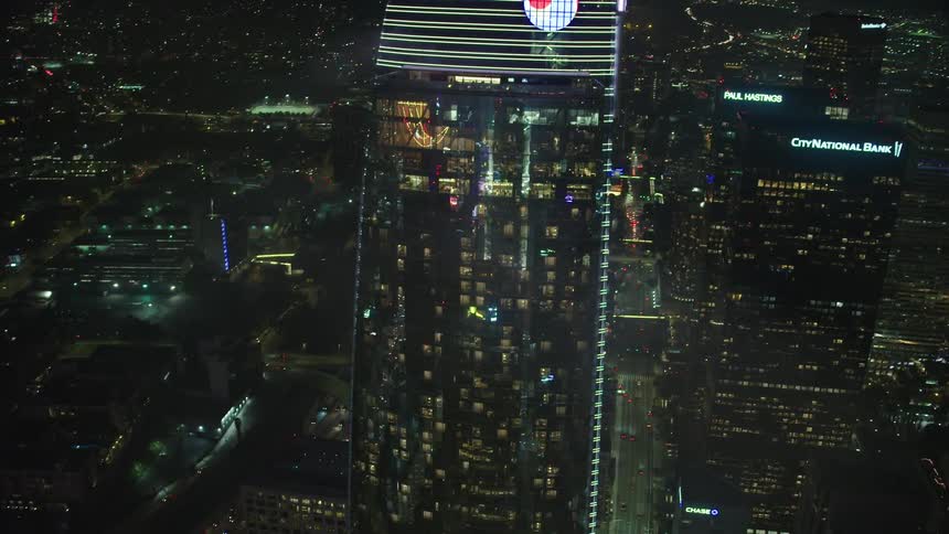 The buildings are brightly lit at night as the cars travel