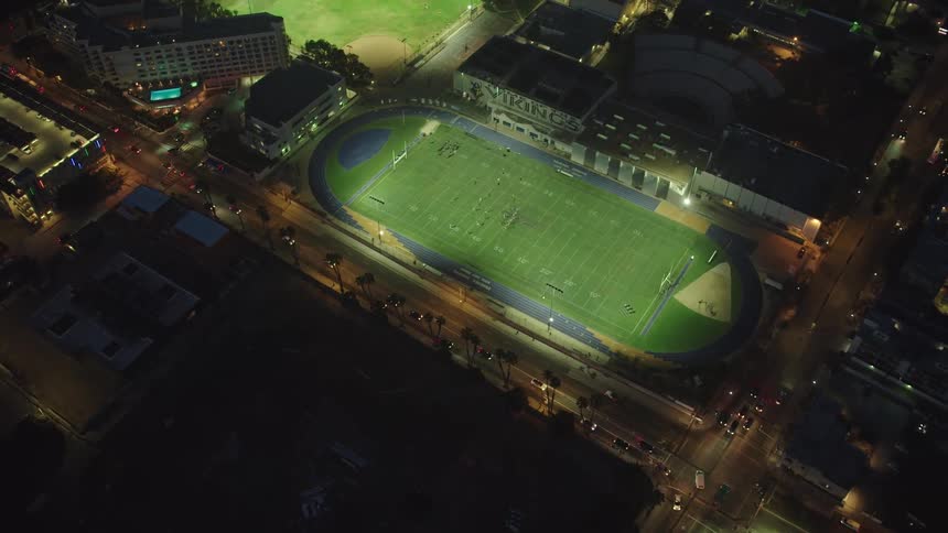 Sports fields remain brightly lit as traffic passes along city streets at night