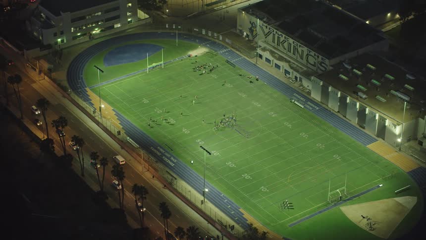 A school football field illuminated by flood nights during the night