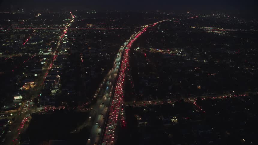 A large freeway through a metropolis illumination by head and tail lights